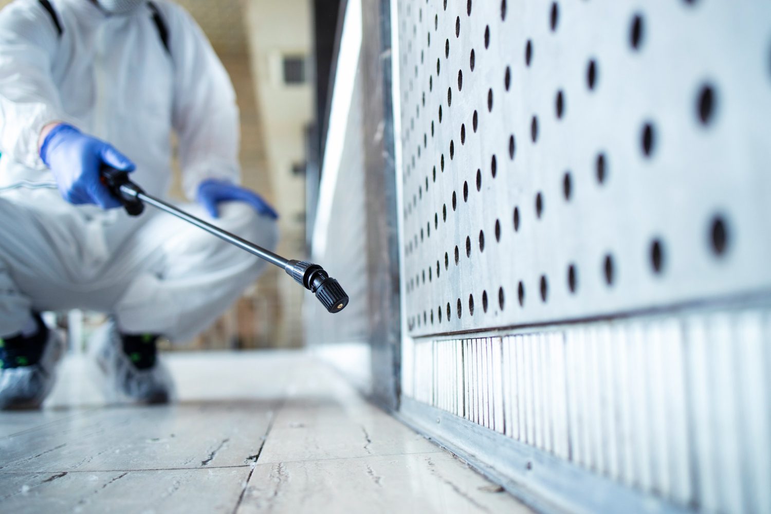 unrecognizable person in white chemical protection suit doing disinfection of public areas to stop spreading highly contagious